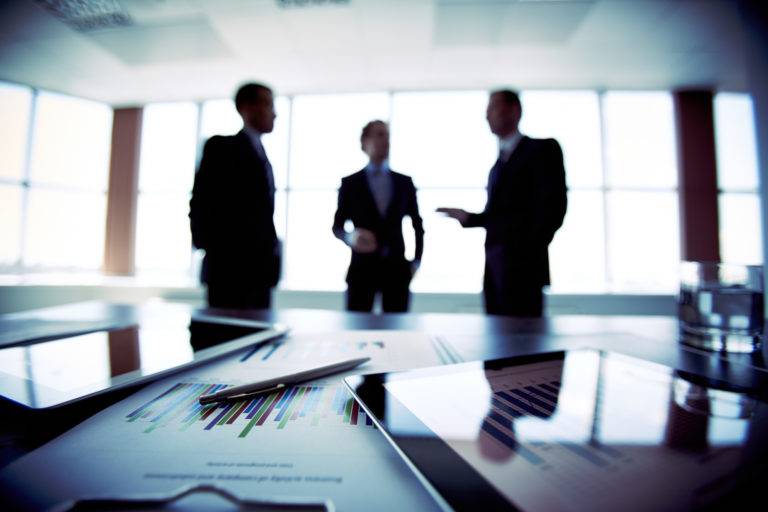 close up documents with businessmen blurred background 768x512 1